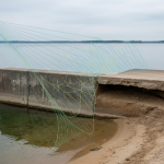 Ground-penetrating radar (GPR) equipment scanning soil near a Lake Conroe bulkhead, illustrating non-invasive diagnostics for potential sub-slab erosion and structural failures.