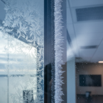 Close-up showing cold-bridge condensation within a Clear Lake office glass-curtain wall, illustrating the HVAC mold issues discussed in 'Clear Lake HVAC Mold Remediation & Cold-Bridge Fixes'.
