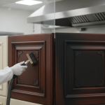 Close-up of a restoration specialist meticulously removing soot from a custom wood kitchen panel, illustrating Bellaire's surgical fire damage remediation.