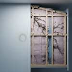 A close-up photograph capturing a subtle area of moisture discoloration on an interior wall near a window frame, indicating potential hidden water damage or mold often associated with the 'Cold-Bridge Effect' in modern transitional homes. This visual is typical of the complex issues we address in water damage restoration services throughout Cypress, TX.