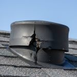 Close-up of a severely cracked black rubber roof pipe boot on a residential shingle roof, a common failure point requiring expert water restoration services in Houston due to resultant ceiling leaks and water damage.