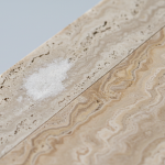 Close-up comparison detailing the distinct surface damage of travertine etching versus water staining, as explained in our stone restoration guide.