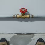 A person's hand turning a water shut-off valve, a key immediate action for emergency water extraction before 24/7 Restoration Specialists arrive.