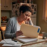 Homeowner at a kitchen table with an insurance folder